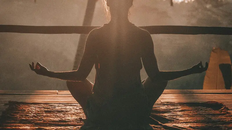 Person meditating peacefully indoors in soft morning light